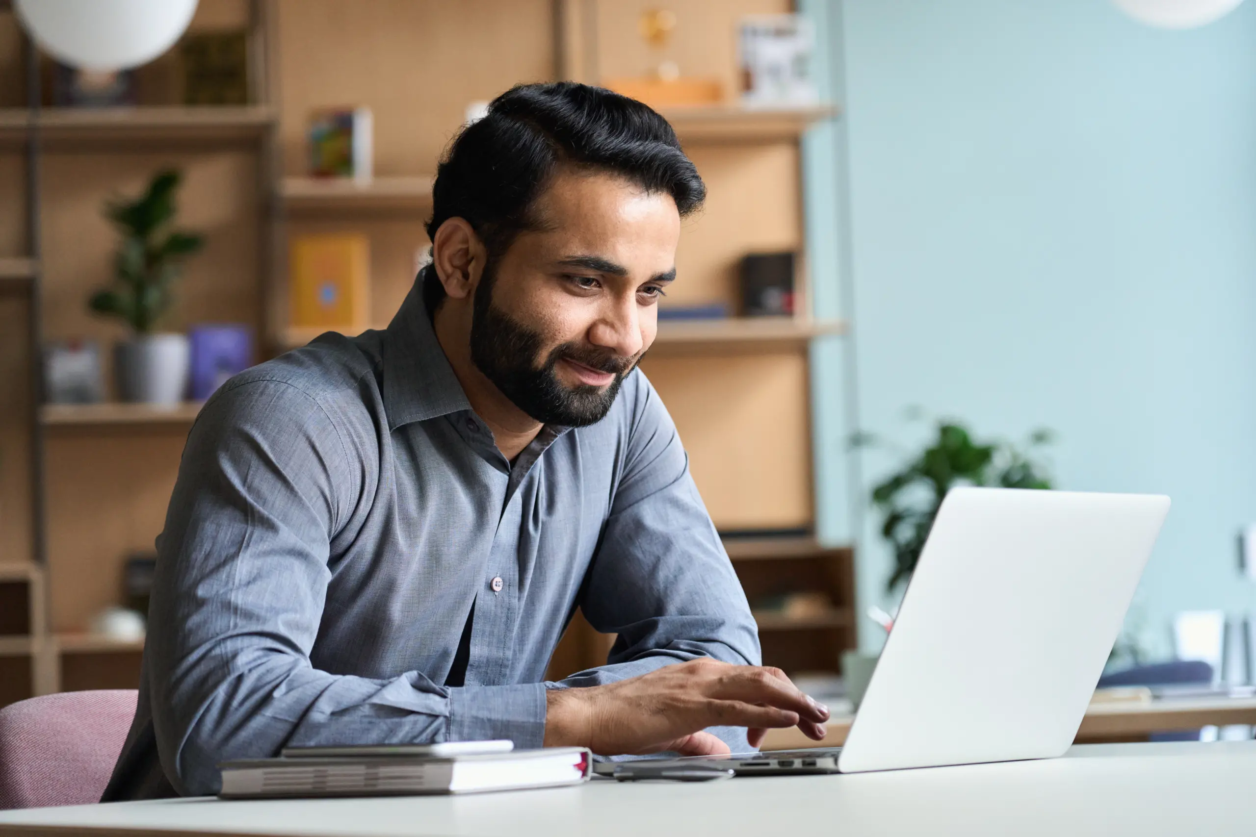 Smiling Indian Business Man Working Studying On Laptop Computer At Home Office.